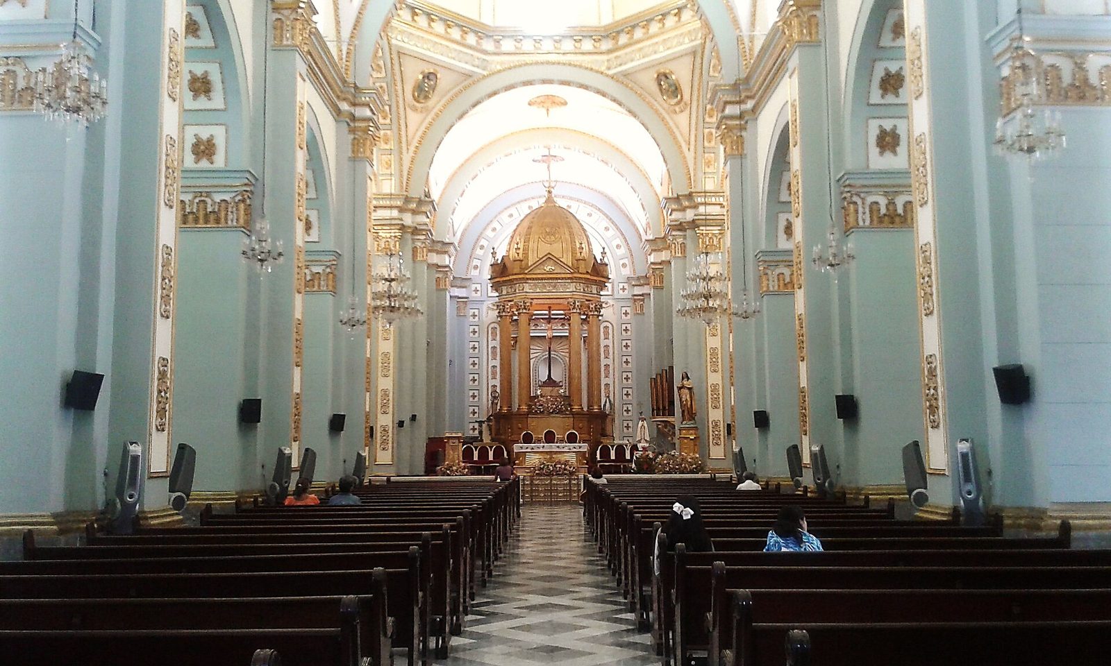 Nave hacia el altar mayor. Se ven el dorado del presbiterio, las pilastras y la luz de la cúpula.